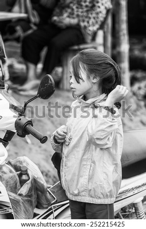 TA PHIN, LAO CAI, VIETNAM - SEP 21, 2014:  Unidentified Red Dao girl in orange jacket checks her look in a motocycle mirror. Red Dao is one of the minority ethnic groups in Vietnam