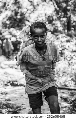 OMO, ETHIOPIA - SEPTEMBER 20, 2011: Unidentified Ethiopian boy carries a bag on his back. People in Ethiopia suffer of poverty due to the unstable situation