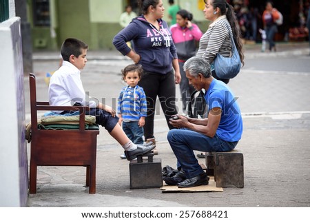RIOBAMBA, ECUADOR - JAN 7, 2015: Unidentified Ecuadorian man cleans shoes to a boy. 71,9% of Ecuadorian people belong to the Mestizo ethnic group