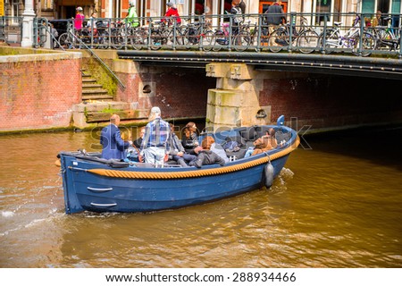 AMSTERDAM, NETHERLANDS - JUN 1, 2015: Boat floating on the Canal of Amsterdam. Amsterdam is the capital city and most populous city of the Kingdom of the Netherlands