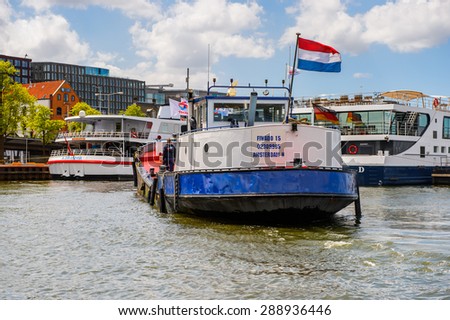 AMSTERDAM, NETHERLANDS - JUN 1, 2015: Floating boats on the Canal of Amsterdam. Amsterdam is the capital city and most populous city of the Kingdom of the Netherlands