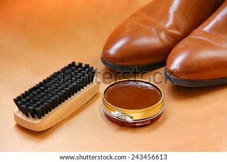 Brown boots with shoe polish and brush shoe care background.