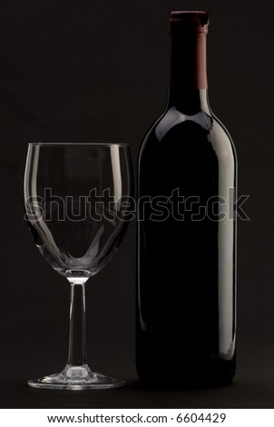 A Bottle of red wine with a wine glass on a plain background