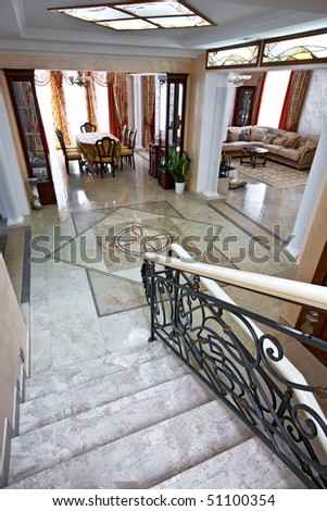 Luxury home interior with staircase, lobby, living room and table for dinner in daylight
