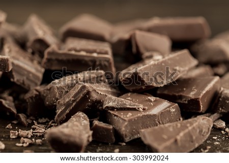 Broken chocolate bar on wooden background, close-up