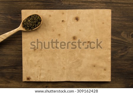 Oolong tea spoon in the old blank open book on wooden background. Menu, recipe, mock up