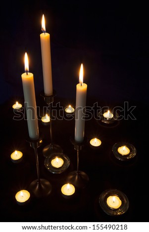 Lit candles and tealights on a dark background.
