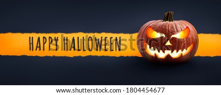 The words Happy Halloween on a textured paper tear with a Halloween Lantern, Jack O Lantern on dark blue banner background