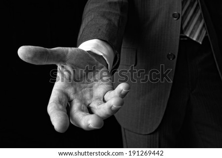 A businessman holding out his hand to shake the hand of another.