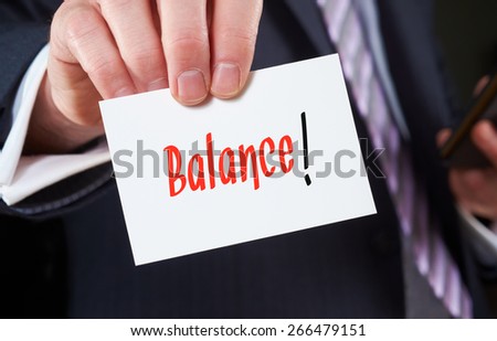 A businessman holding a business card with the words, Balance, written on it.