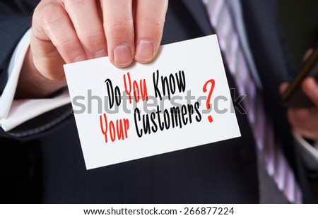 A businessman holding a business card with the words, Di You Know Your Customers?, written on it.
