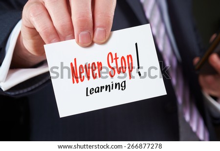 A businessman holding a business card with the words, Never Stop Learning, written on it.