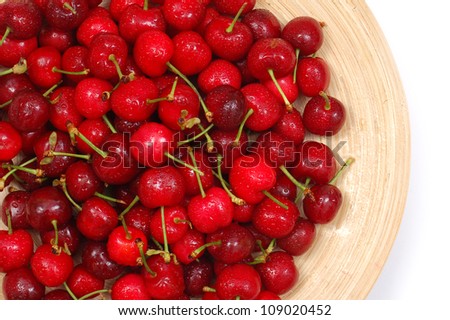 Wet cherries in wooden plate, isolated, closeup.Fresh fruits.