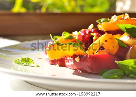 Colorful vegetables salad in white plate sunlight from window.Roasted sweet peppers,garlic and fresh basil salad. Healthy, dieting, veg food.