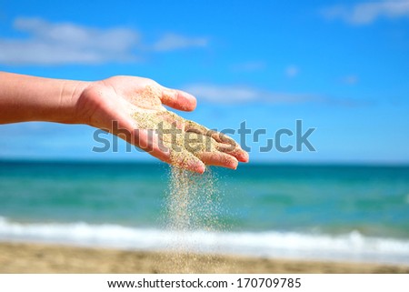 Sand falling from the woman\'s hand on tropical beach. Concept beach vacation, travel time, relax.