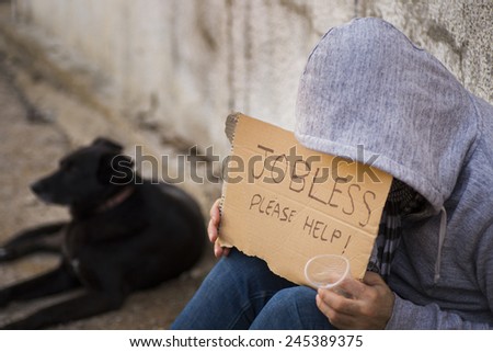 Close up of poor young guy with cartboard sign seeking help
