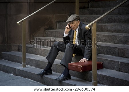 NEW YORK CITY - APRIL 21: Elegant senior man with suite and business suite sitting on building stairs and talking on the phone.  Shot on April 21, 2015 in New York, New York.
