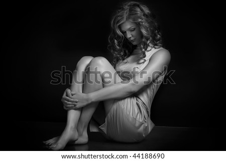 Sad woman sitting on black background