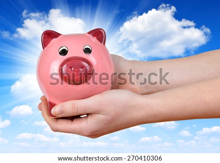 Woman hand holding a pink piggy bank