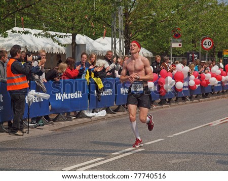 COPENHAGEN - MAY 21: Male runner crossing the finish line at the yearly Copenhagen Marathon. It covers a 42- kilometer route within the city centre in Copenhagen, Denmark on May 21, 2011.
