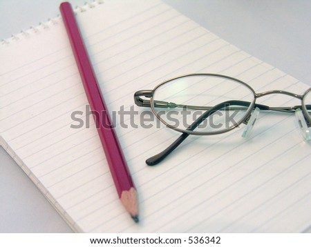A pair of glasses on a blank note pad with a pencil.