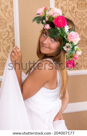 girl with wreath on his head on background of beige classic wall