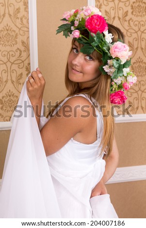 young woman with wreath on his head on background of beige wall