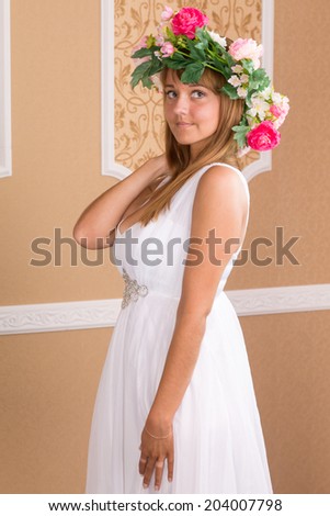 portrait young woman with wreath on his head on background of beige classic wall
