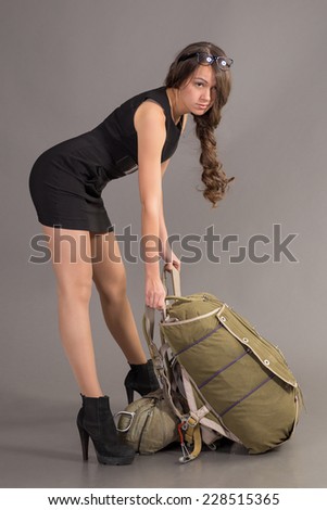 brunette in short black dress holding satchel of parachute