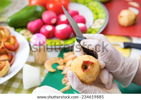 Clean apple in white disposable gloves on the background vegetables on a plate