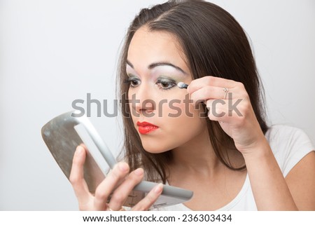 Brunette color eye shadows look in the mirror on white background