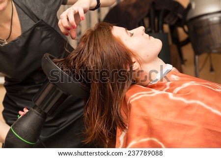 hairdresser dries the hair client hairdryer with special nozzle in salon
