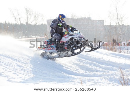Perm, Russia - February 23, 2015. Championship on Cross Country Snowmobile. Rider on black snowmobile jumped over hill in winter