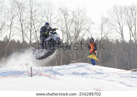 Perm, Russia - February 23, 2015. Championship on Cross Country Snowmobile. man on black snowmobile jumped over  hill