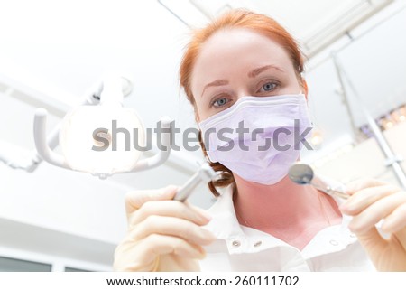 Drill and mirror in  hands of the dentist. Face in Focus