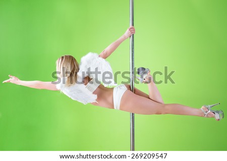 sexy girl in white shorts and angelic wings makes  element superman  at pole dance