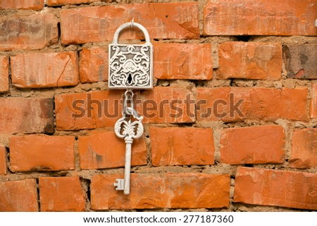 Vintage silver lock and key hanging on  brick wall