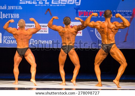 Perm, Russia - April 19, 2015.Cup Perm Krai  on bodybuilding and fitness bikini. Three bodybuilders are back on stage showing double biceps