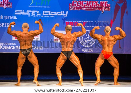 Perm, Russia - April 19, 2015.Cup Perm Krai  on bodybuilding and fitness bikini. Three bodybuilder standing with his back to the judges and show a double biceps