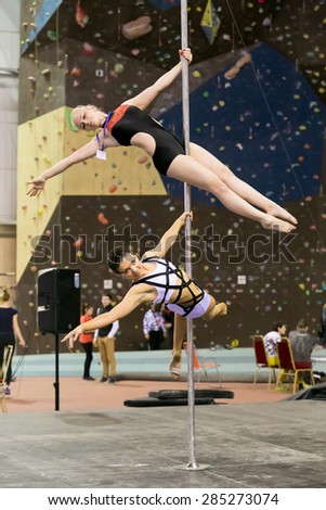 Perm, Russia - April 25, 2015. Championship Perm region at pole sport and dance. blonde in a black suit with a bright pattern and brunette in black and white suit on a pole makes the element string