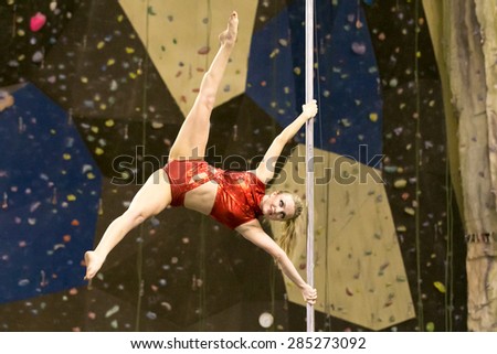 Perm, Russia - April 25, 2015. Championship Perm region at pole sport and dance. Blonde with bright makeup in a red costume makin element  Twisted x-flag