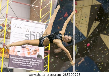 Perm, Russia - April 25, 2015. Championship Perm region at pole sport and dance.  The brunette in a black costume making element Twisted x-flag