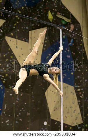 Perm, Russia - April 25, 2015. Championship Perm region at pole sport and dance. The blonde in a black swimsuit makes a element Twisted x-flag