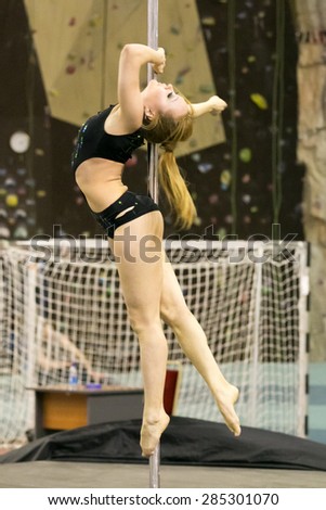 Perm, Russia - April 25, 2015. Championship Perm region at pole sport and dance. The blonde in a black swimsuit makes a element  hook on the elbow with a deflection