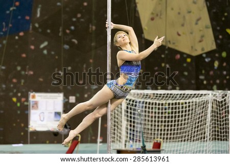 Perm, Russia - April 25, 2015. Championship Perm region at pole sport and dance. blonde in a blue swimsuit with patterns making element superman