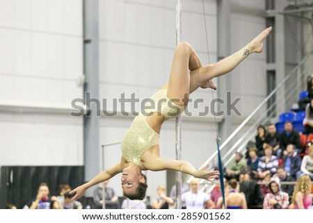 Perm, Russia - April 25, 2015. Championship Perm region at pole sport and dance. Brunette in gold swimsuit makes element Jasmine