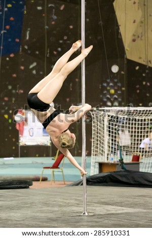 Perm, Russia - April 25, 2015. Championship Perm region at pole sport and dance. little blonde does element flag with a hook on one elbow upside down