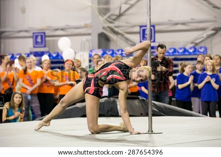 Perm, Russia - April 25, 2015. Championship Perm region at pole sport and dance.  blonde in a black swimsuit with a pink pattern dance near pole