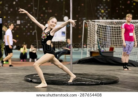 Perm, Russia - April 25, 2015. Championship Perm region at pole sport and dance. Teen girl in a black swimsuit with a gold pattern performs at competitions and smile