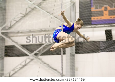 Perm, Russia - April 25, 2015. Championship Perm region at pole sport and dance. Little brunette in blue swimsuit makes element fold variations